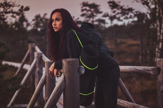 La estudiante está revisando el tiempo en su reloj mientras se apoya en la barandilla en medio del bosque.