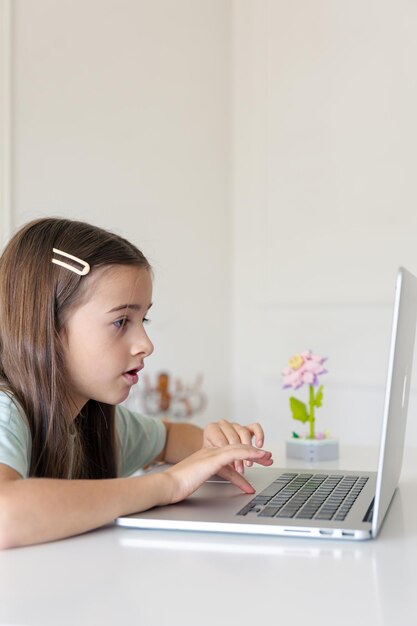 Una estudiante estudia en línea en casa. La chica está escribiendo en el teclado de la computadora portátil.