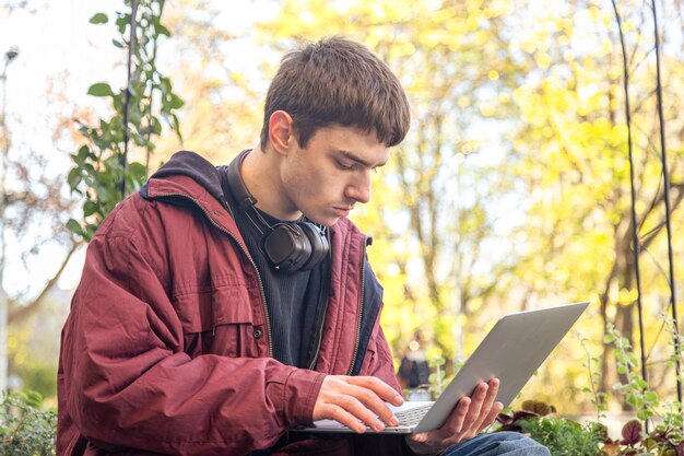 Un estudiante estudia usando una computadora portátil Estudiante masculino estudiando en línea