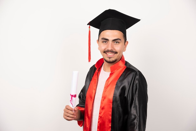 Estudiante feliz con diploma posando en blanco.