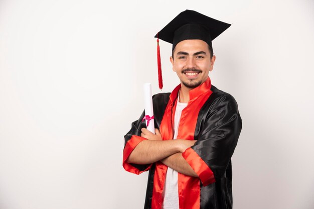 Estudiante feliz con diploma posando en blanco.