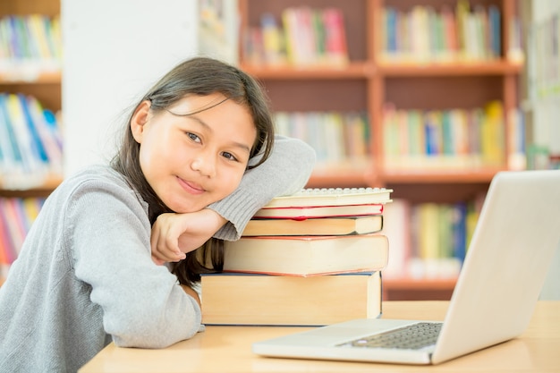 estudiante feliz niña o niña con libro en la biblioteca.