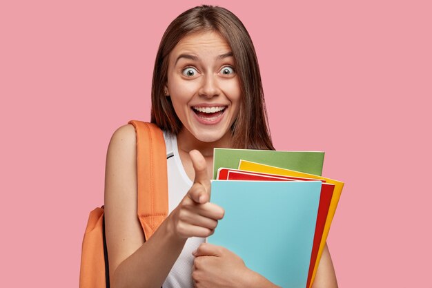 Estudiante feliz posando contra la pared rosa