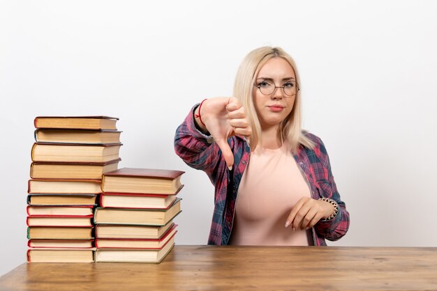 estudiante femenina sentada con libros en blanco claro