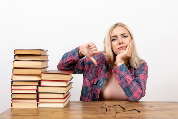 estudiante femenina sentada con libros en blanco