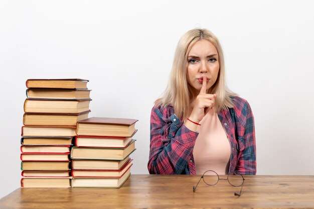 estudiante femenina sentada con libros en blanco