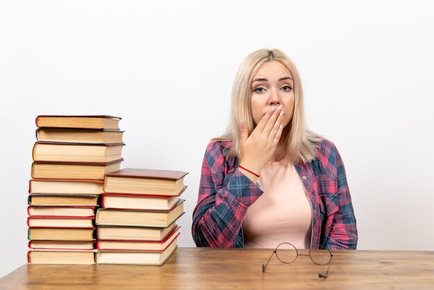 estudiante femenina sentada con libros en blanco