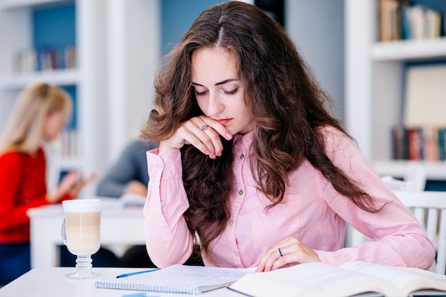 Foto gratuita estudiante femenino que estudia en biblioteca