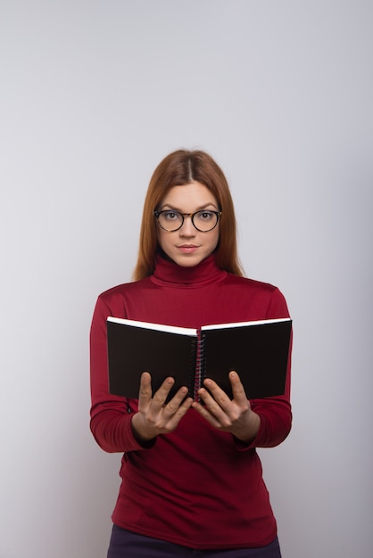 Estudiante femenino que sostiene el cuaderno y que mira