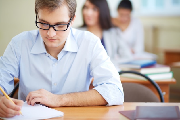 Estudiante con gafas escribiendo