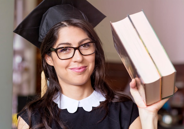 Foto gratuita estudiante con gorro de graduación sujetando dos libros