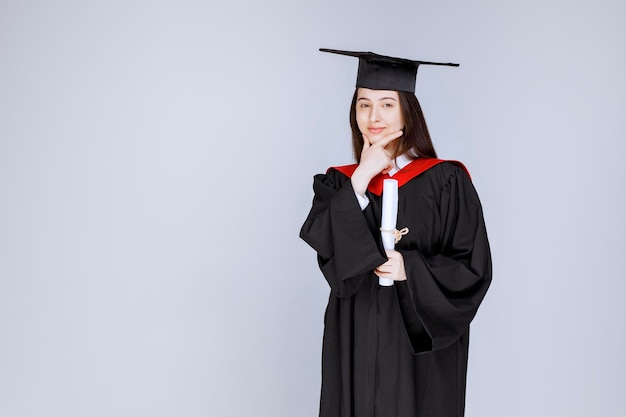 Estudiante graduada mostrando su diploma. Foto de alta calidad