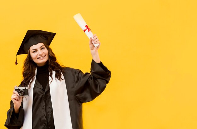 Estudiante graduado con cámara y diploma.