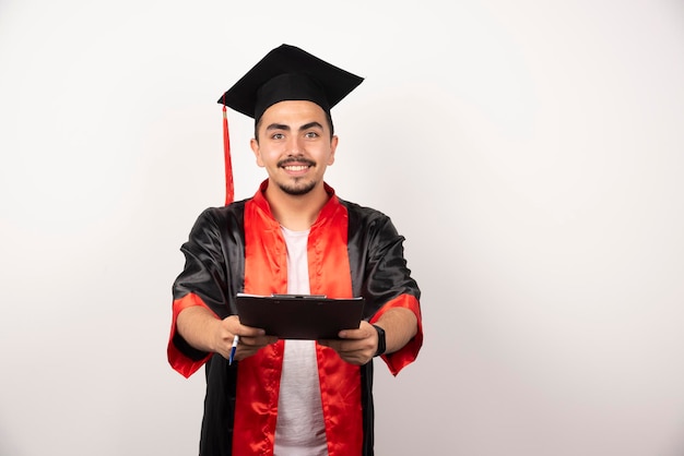 Foto gratuita estudiante graduado positivo mostrando diploma en blanco.