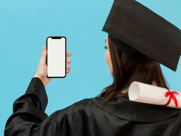 Foto gratuita estudiante graduado con teléfono inteligente