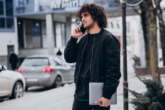 Estudiante guapo con pelo rizado usando laptop