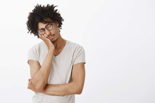 Estudiante guapo soñoliento que parece cansado, acostado en la palma y tomando la siesta