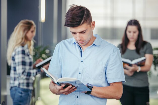 Estudiante hombre leyendo en la biblioteca