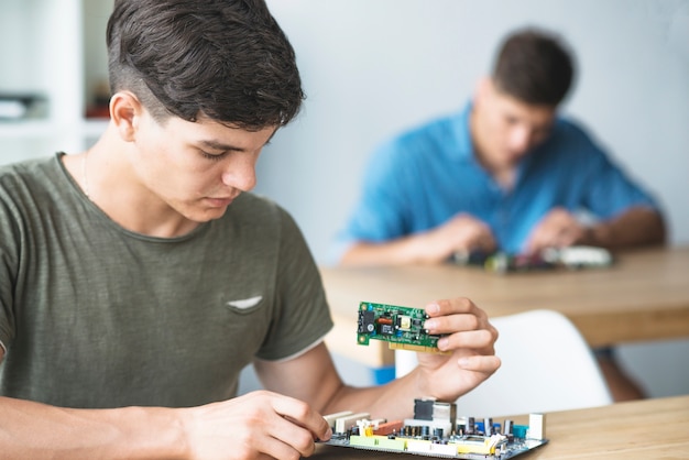 Estudiante de ingeniería aprendiendo a arreglar el componente electrónico en la placa base de la computadora