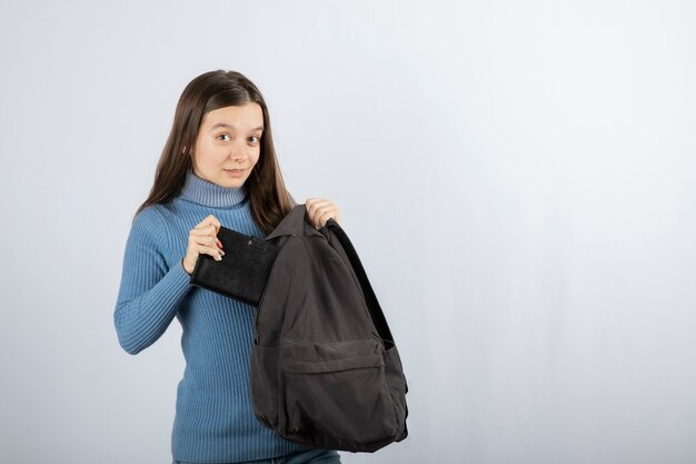 estudiante joven poniendo el cuaderno en la mochila.