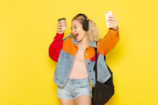 estudiante joven en ropa moderna escuchando música bailando en amarillo