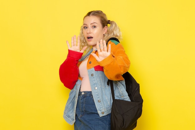 Foto gratuita estudiante joven en ropa moderna posando con precaución en amarillo