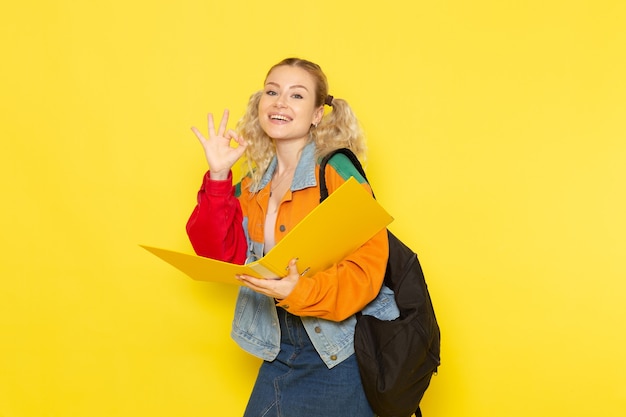 Estudiante joven en ropa moderna sosteniendo el archivo y sonriendo en amarillo