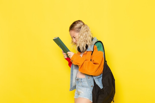 Estudiante joven en ropa moderna sosteniendo cuaderno en amarillo