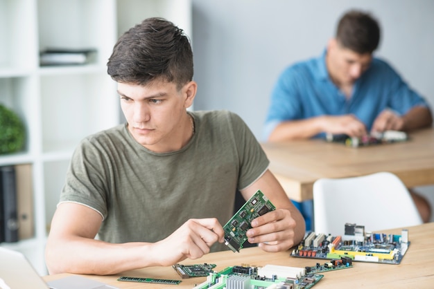 Estudiante joven de TI practicando equipos de hardware en el banco de trabajo