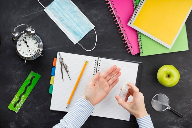 Estudiante laico plano con desinfectante encima del escritorio