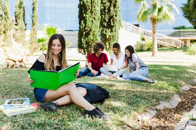 Estudiante leyendo un libro de texto cerca de la universidad