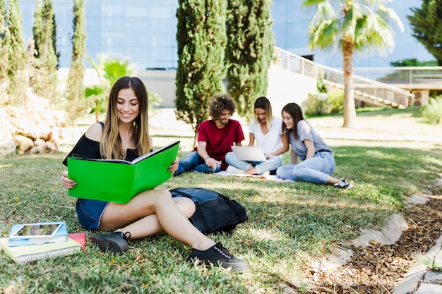 Estudiante leyendo un libro de texto cerca de la universidad