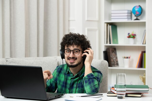 Estudiante en línea chico joven lindo estudiando en la computadora con gafas en camisa verde sonriendo