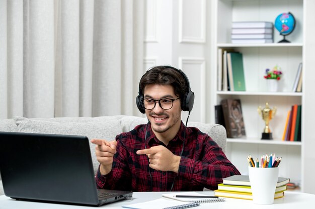 Estudiante en línea chico lindo en camisa a cuadros con gafas estudiando en la computadora sonriendo y feliz