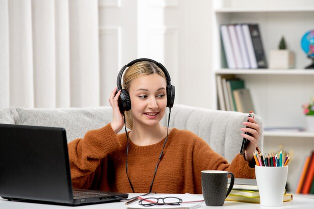 Estudiante en línea linda chica con gafas y suéter estudiando en la computadora tomando una selfie