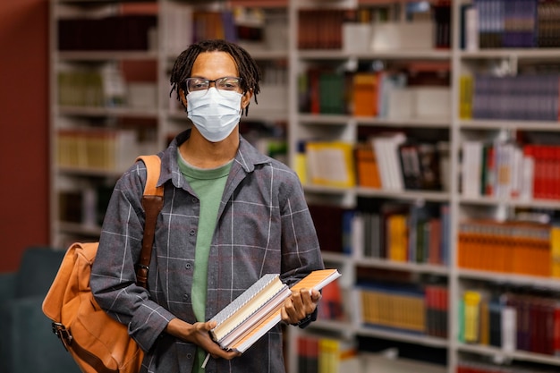 Estudiante con una máscara médica en la biblioteca.