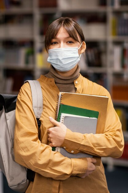 Estudiante con máscaras médicas en la biblioteca.