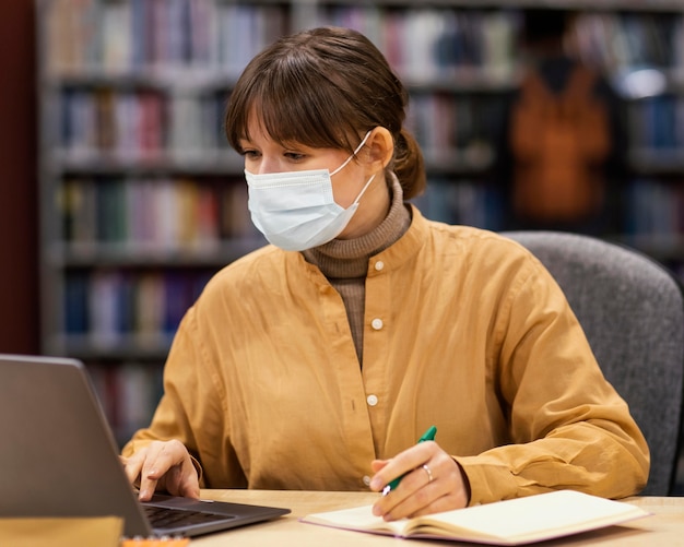 Foto gratuita estudiante con mascarillas en la biblioteca.