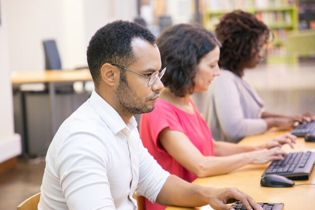 Estudiante masculino adulto serio que estudia en clase de informática