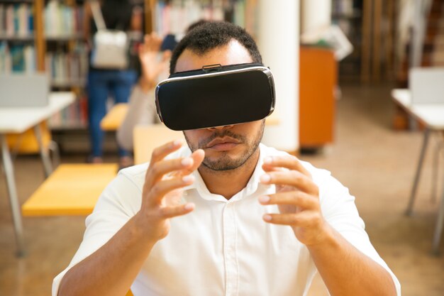 Estudiante masculino emocionado usando simulador de realidad virtual durante la clase