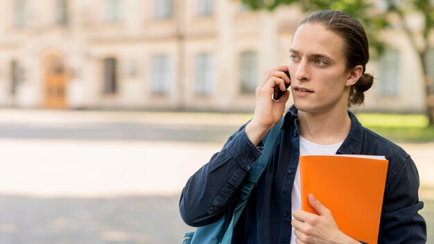 Estudiante masculino guapo hablando por teléfono