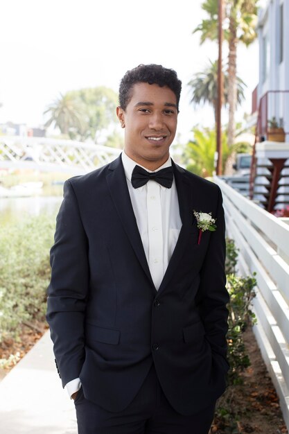 Estudiante masculino listo para el baile de graduación en un traje negro