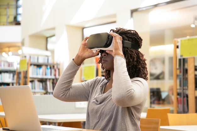 Estudiante mujer negra ajustando auriculares VR