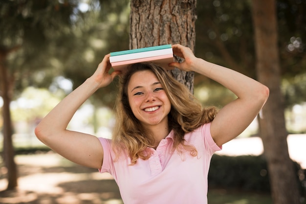 Estudiante mujer sosteniendo libros por encima de la cabeza