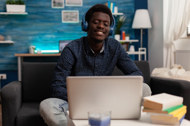 Estudiante negro usando auriculares con curso de negocios de audio en portátil