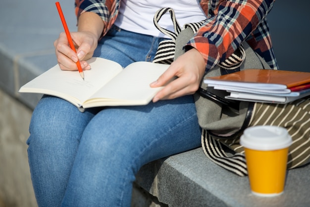 Foto gratuita estudiante niña escribiendo en un cuaderno abierto con un lápiz