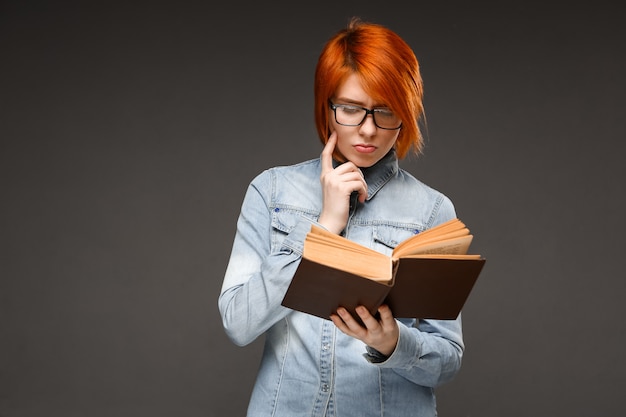 Estudiante pelirroja leyendo libro, estudiando