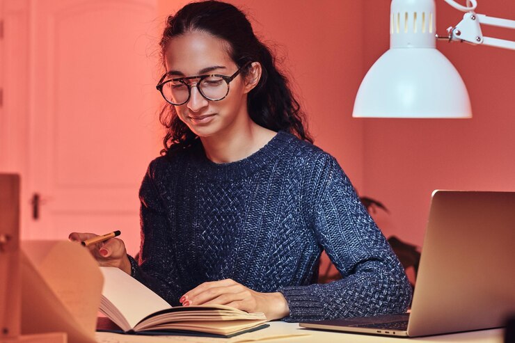 Foto gratuito un estudiante pensativo con anteojos está tomando notas mientras aprende material nuevo.