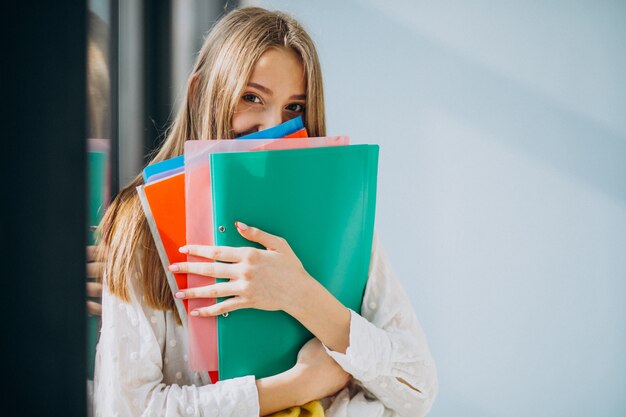 Estudiante de pie con carpetas coloridas