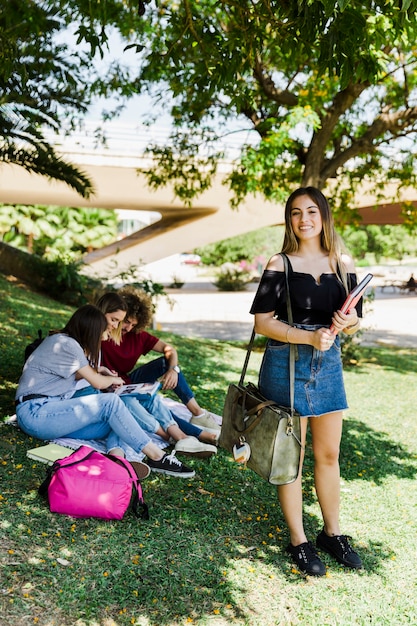 Estudiante de pie con libros de texto en el parque